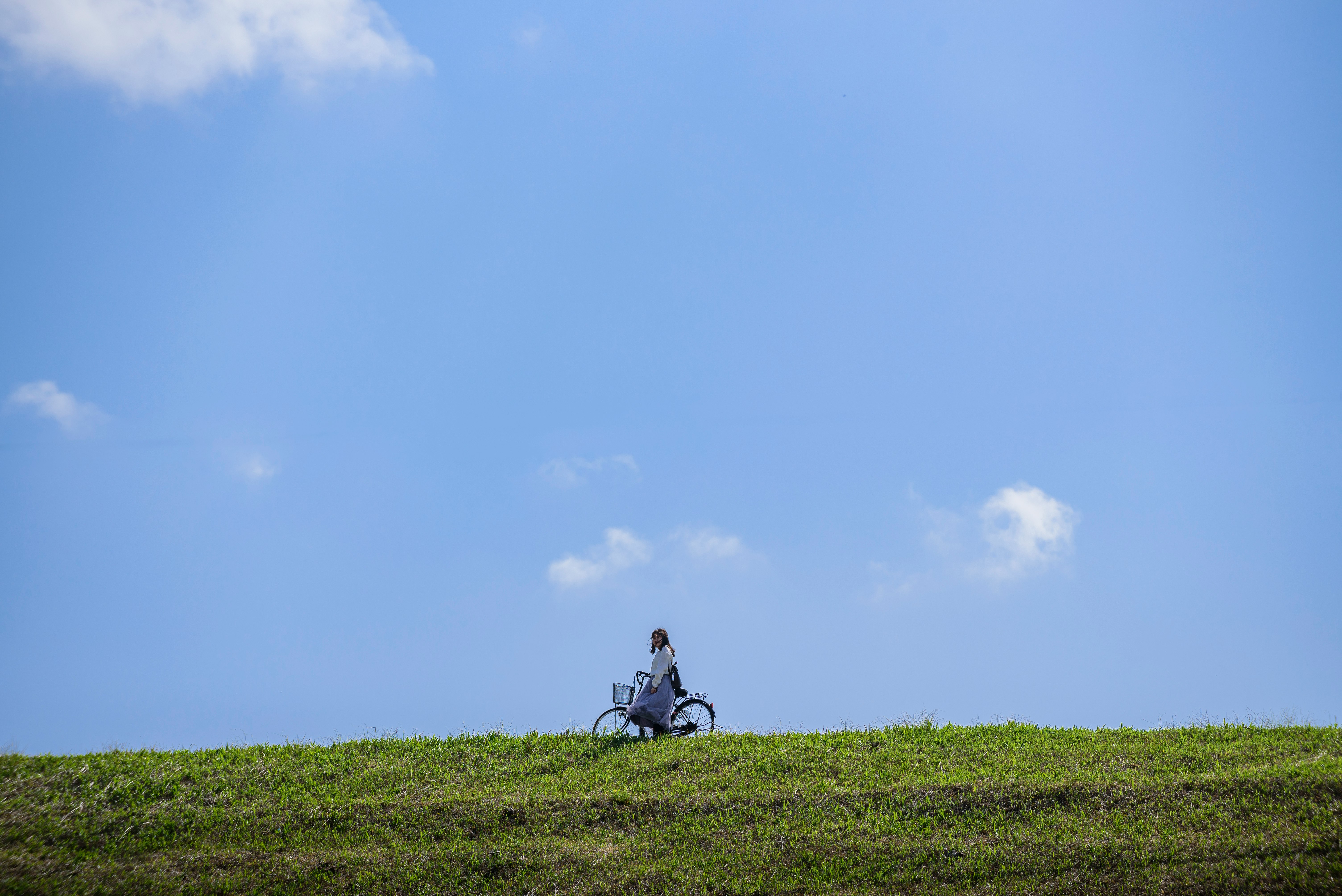 man in black jacket sitting on green grass field under blue sky during daytime