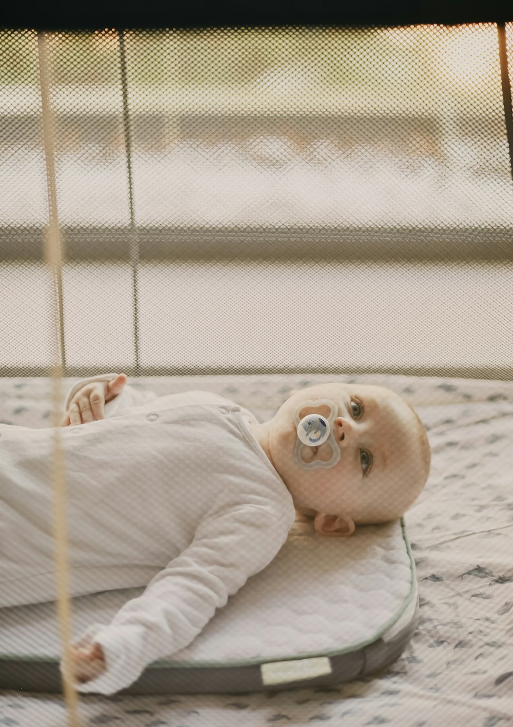 baby in white onesie lying on bed