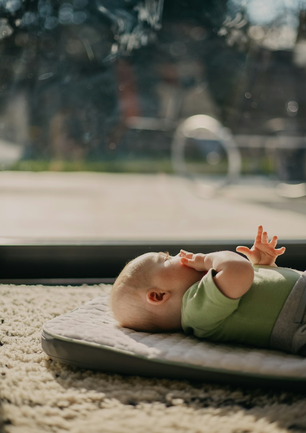 baby in green tank top lying on grey concrete floor