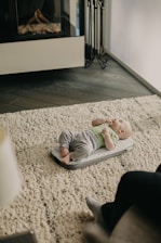 baby in white onesie lying on floor