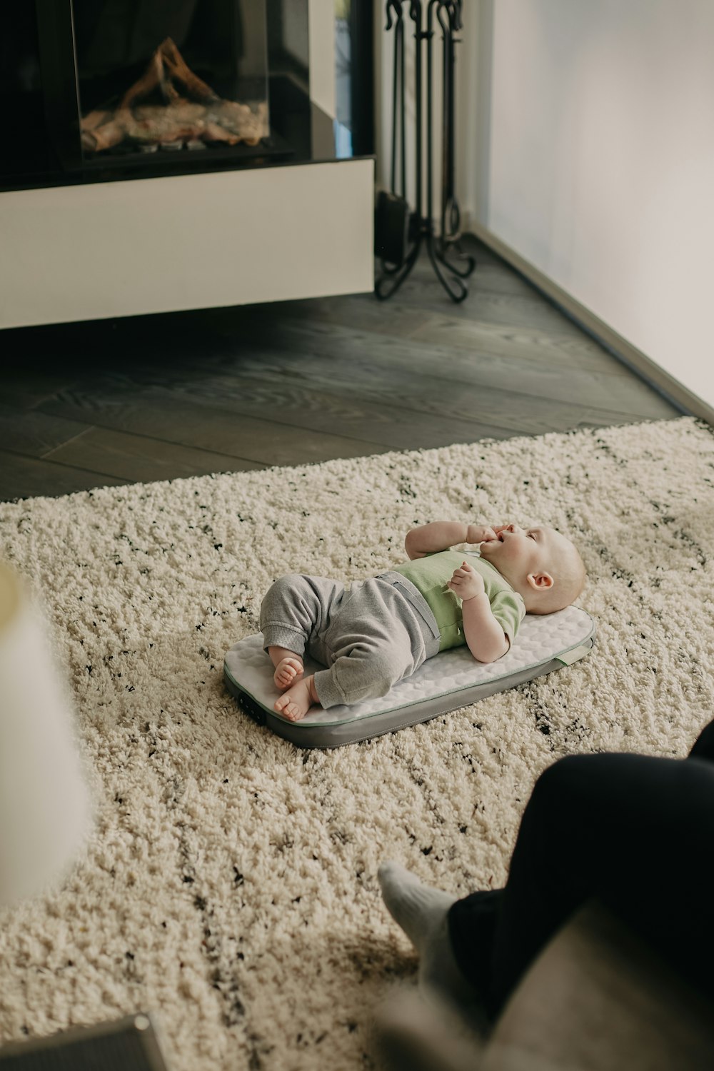 baby in white onesie lying on floor