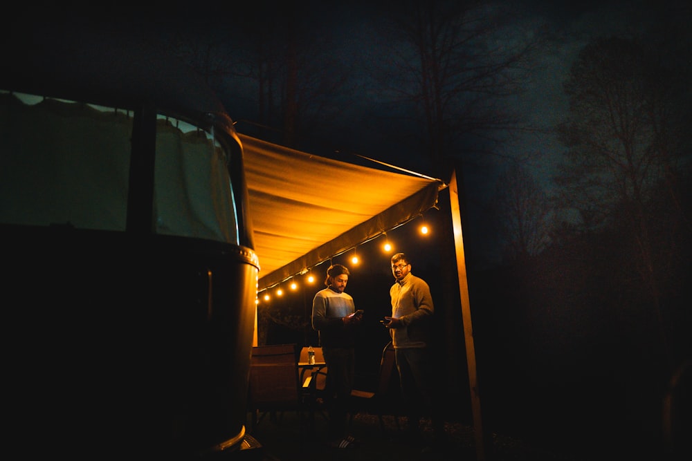 man in black jacket standing near tent during night time