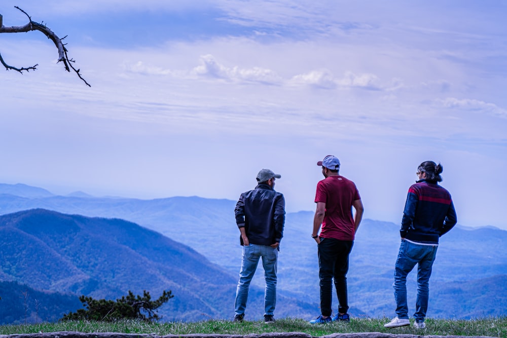 3 men standing on green grass field during daytime