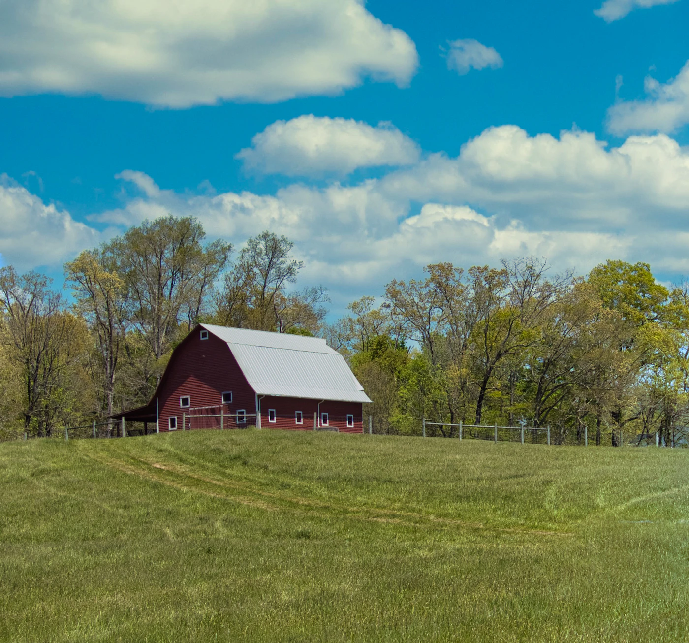 Classic red barn with white trim on a green field under blue sky