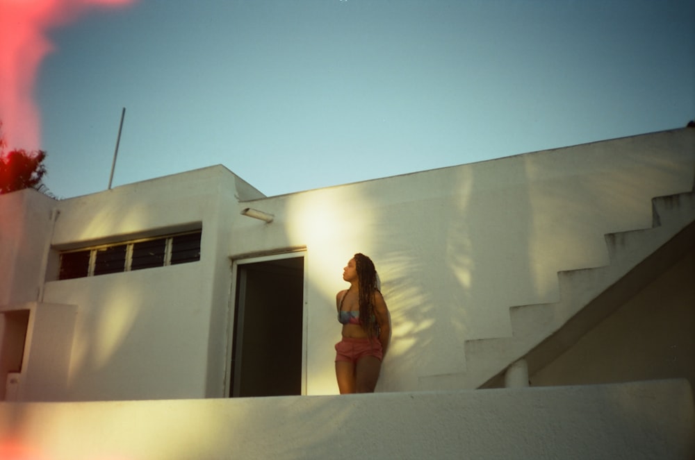 woman in black tank top standing on white concrete building during daytime