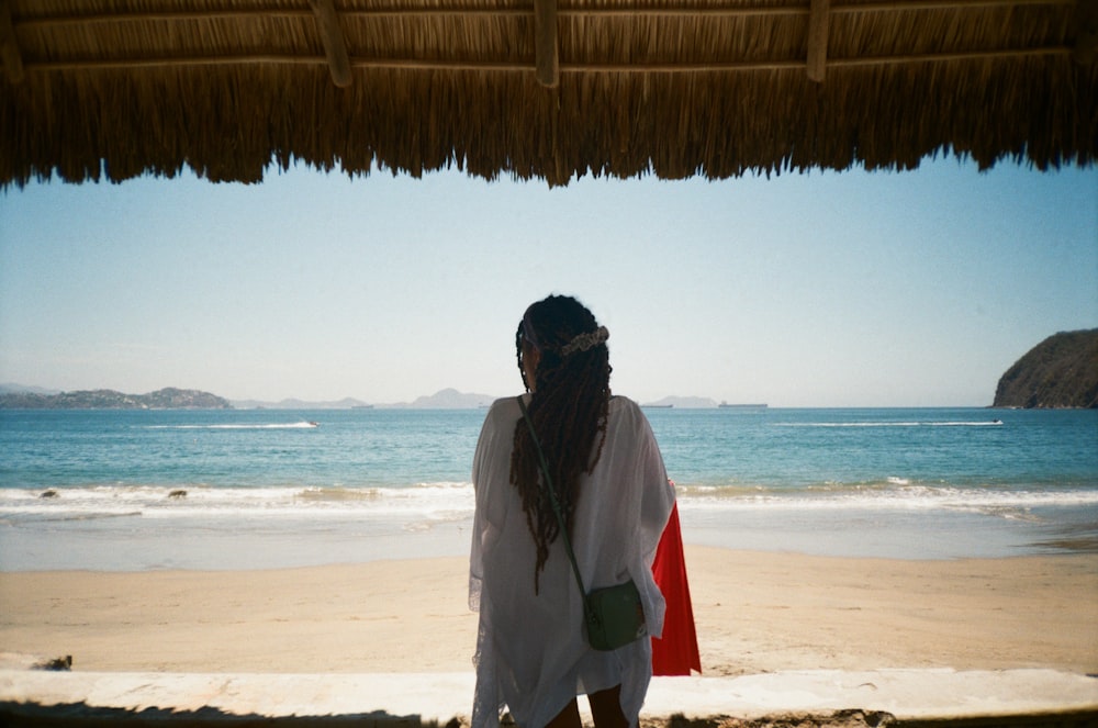 hombre en chaqueta blanca y roja de pie en la playa durante el día