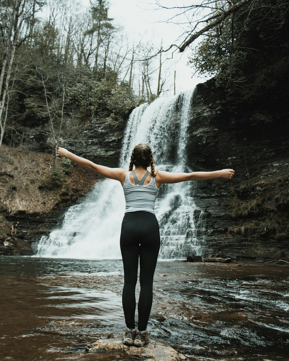 woman in white tank top and black leggings standing on river