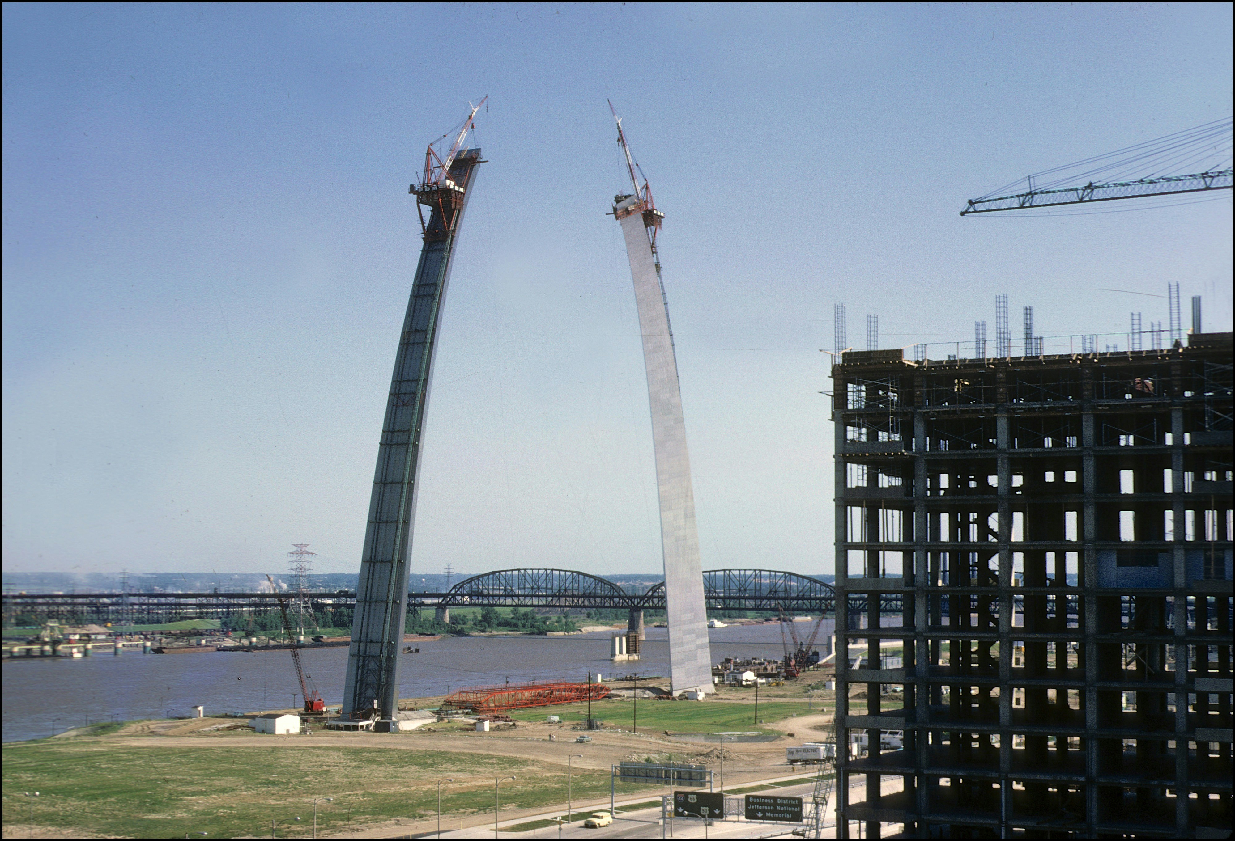 Two tall concrete towers under construction by river.