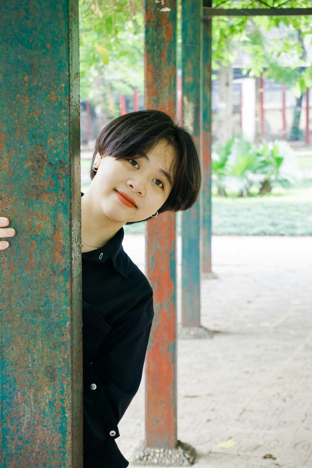 girl in black long sleeve shirt leaning on brown wooden post during daytime