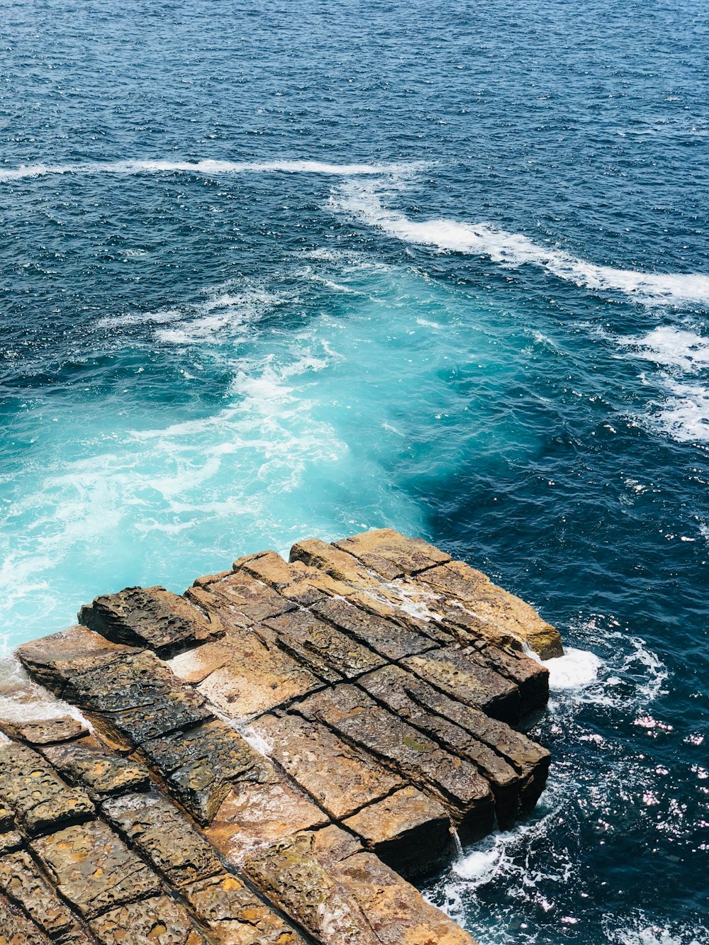 brown rock formation on body of water during daytime