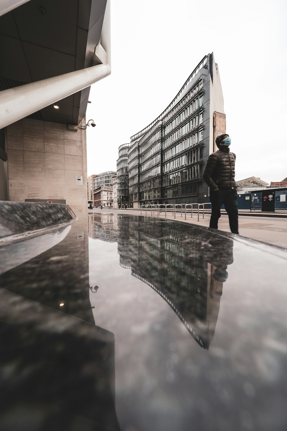 man in black jacket and pants standing on gray concrete floor