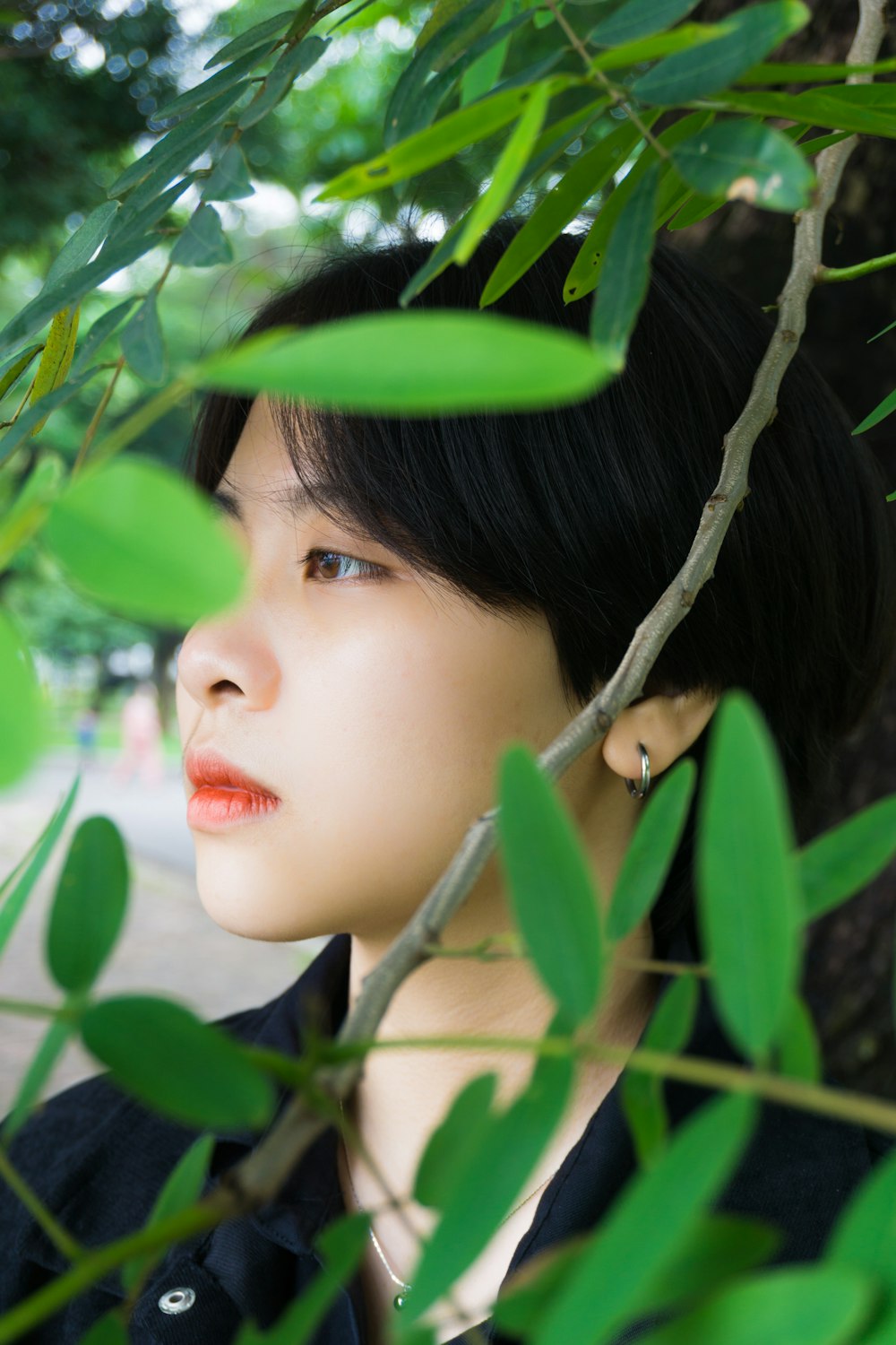 woman in red lipstick hiding behind green leaves