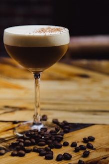 a glass filled with a drink sitting on top of a wooden table