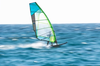 green and white sail boat on sea during daytime