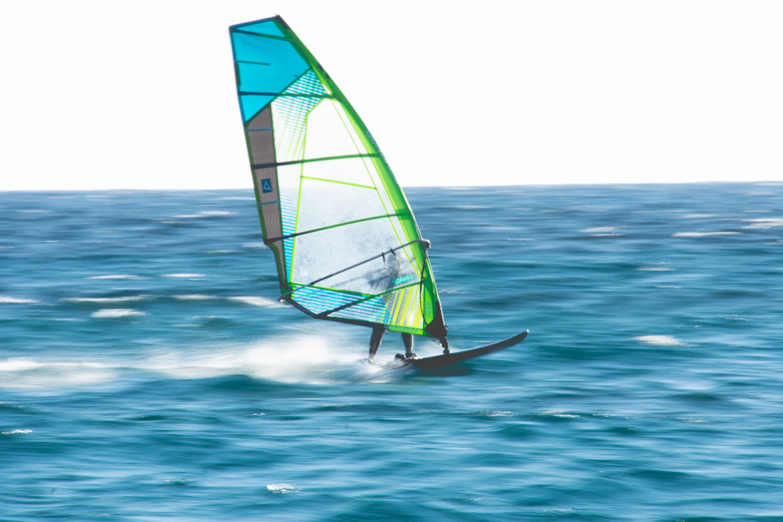 Windsurfer mit Segel auf bewegtem Meer
