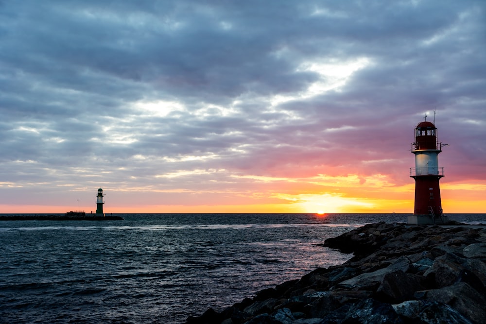 Silueta del faro cerca del cuerpo de agua durante la puesta del sol