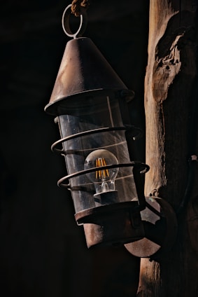 A rustic outdoor post light weathered by time, nestled beside a garden path.