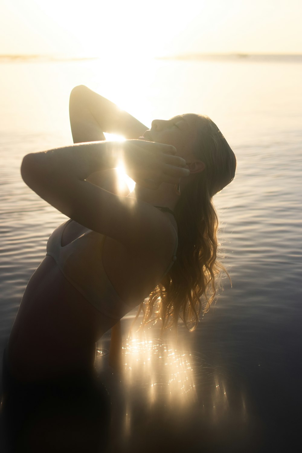 woman in black sun hat on body of water during sunset