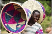 A smiling woman holding a basket of fresh, natural ingredients outdoors.