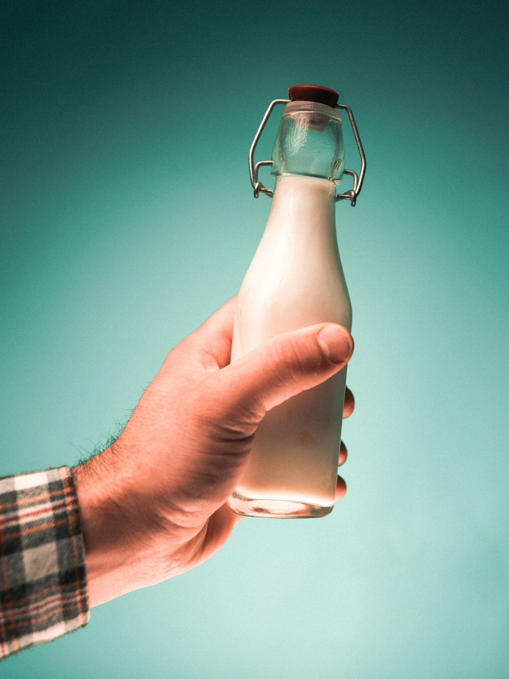 person holding clear glass bottle with water