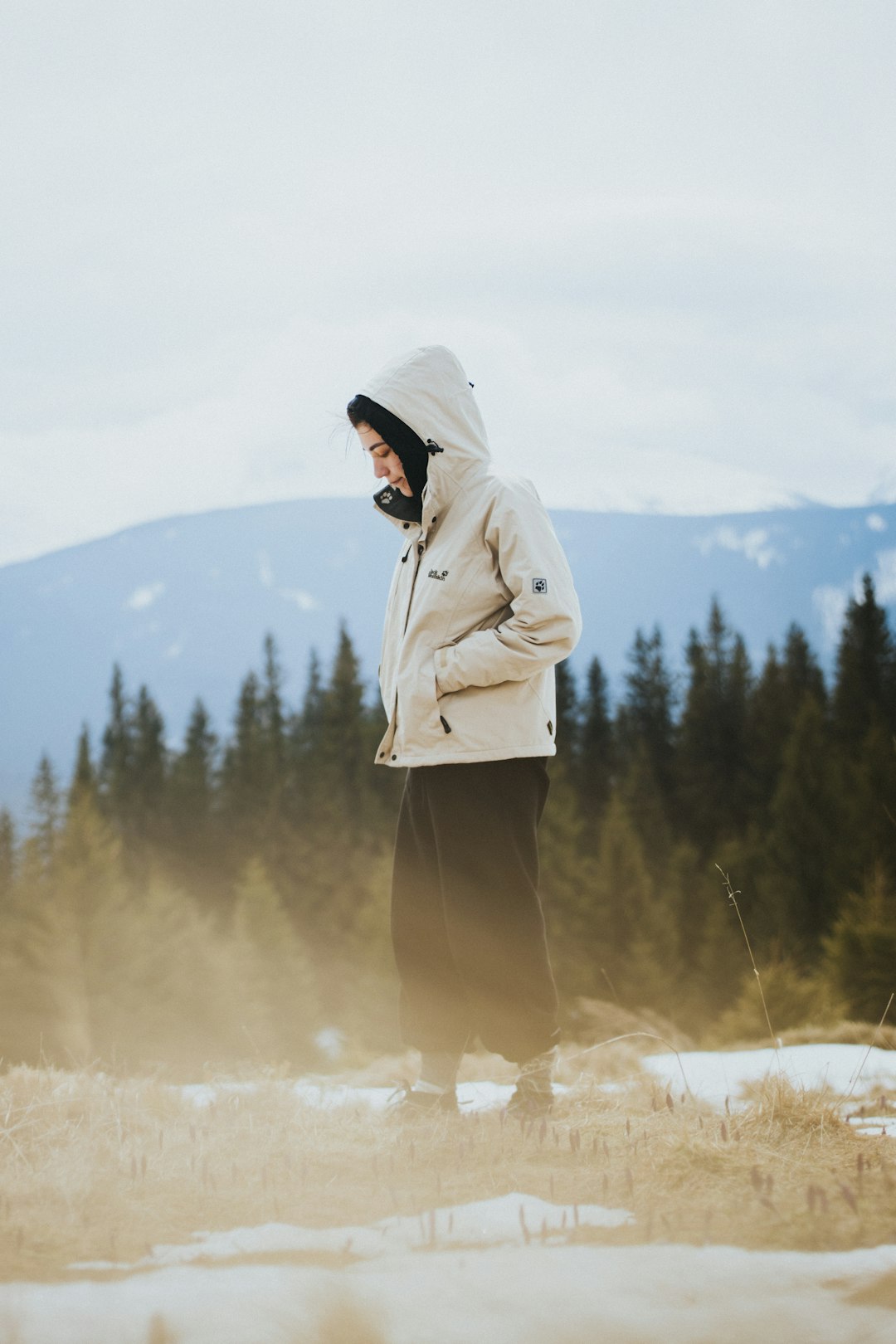 woman in white coat standing on brown grass field during daytime