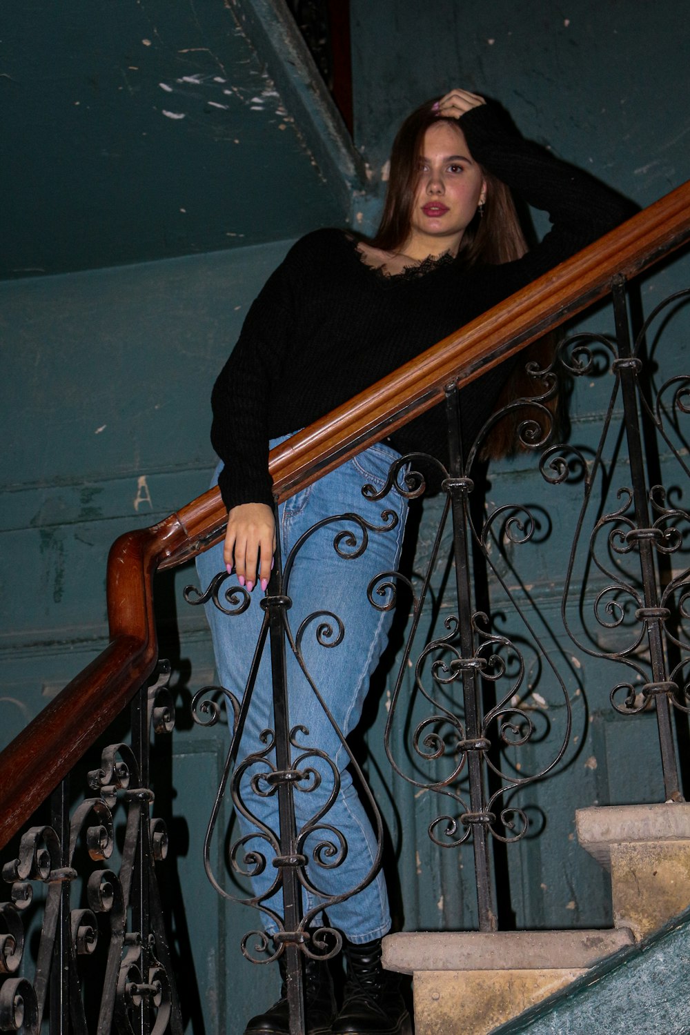 woman in black long sleeve shirt standing beside brown wooden railings