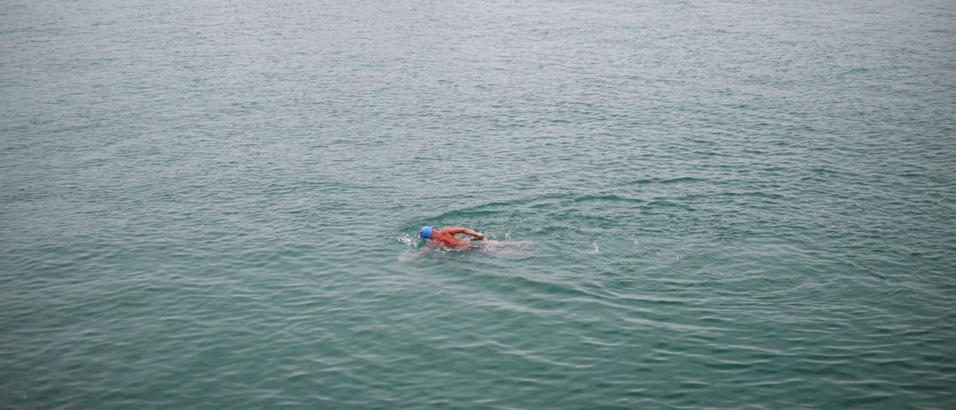 person swimming on body of water during daytime