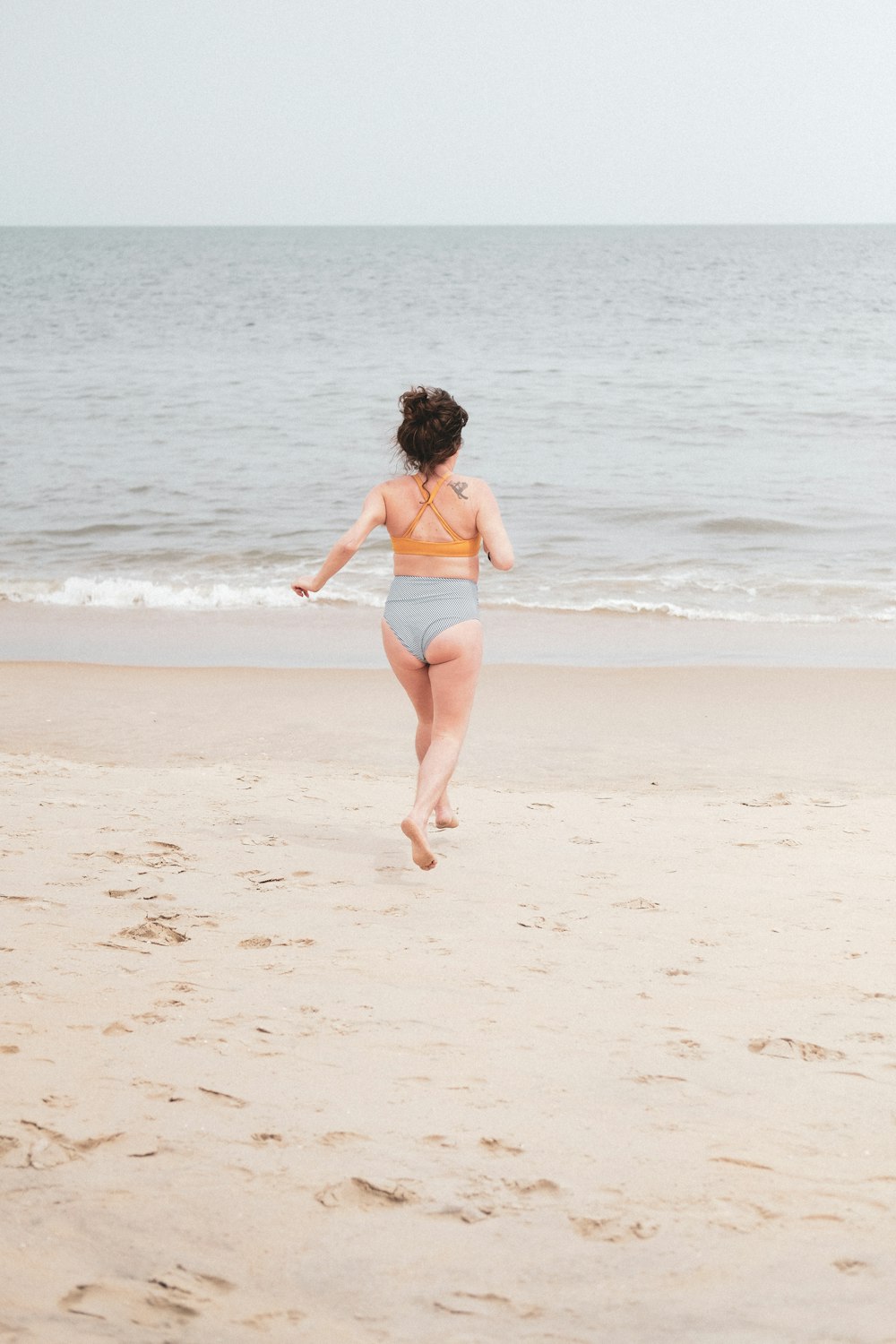 woman in blue denim shorts walking on beach during daytime