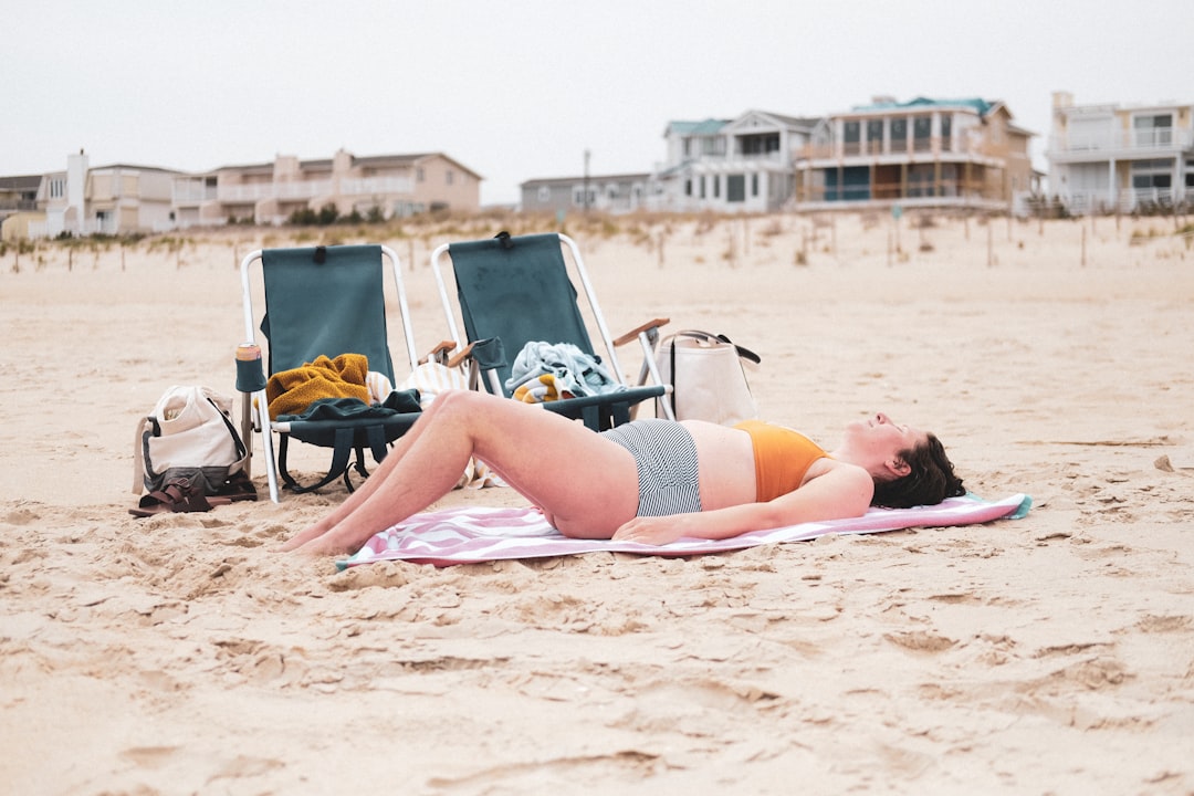 woman in black bikini lying on beach sand during daytime