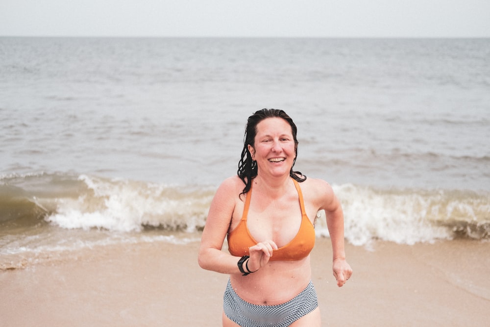 woman in orange bikini standing on beach during daytime