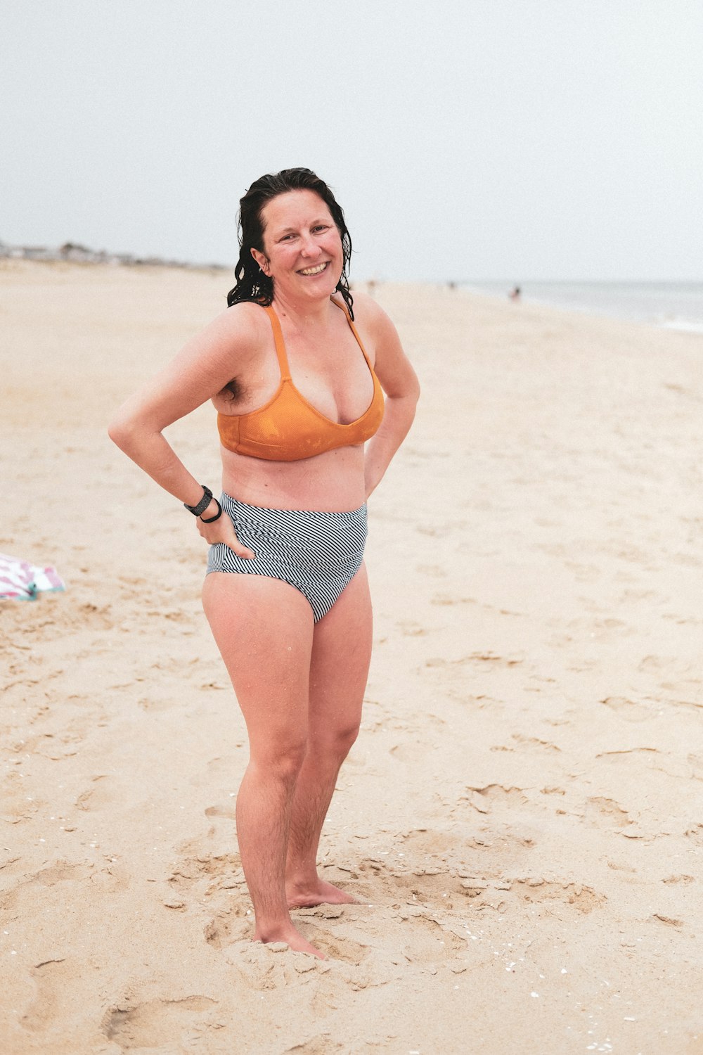 mulher no biquíni preto e branco das bolinhas que posa na praia durante o dia