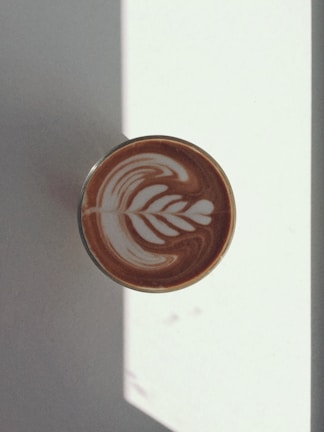 Warm morning light streaming through palm leaves onto a latte with latte art.