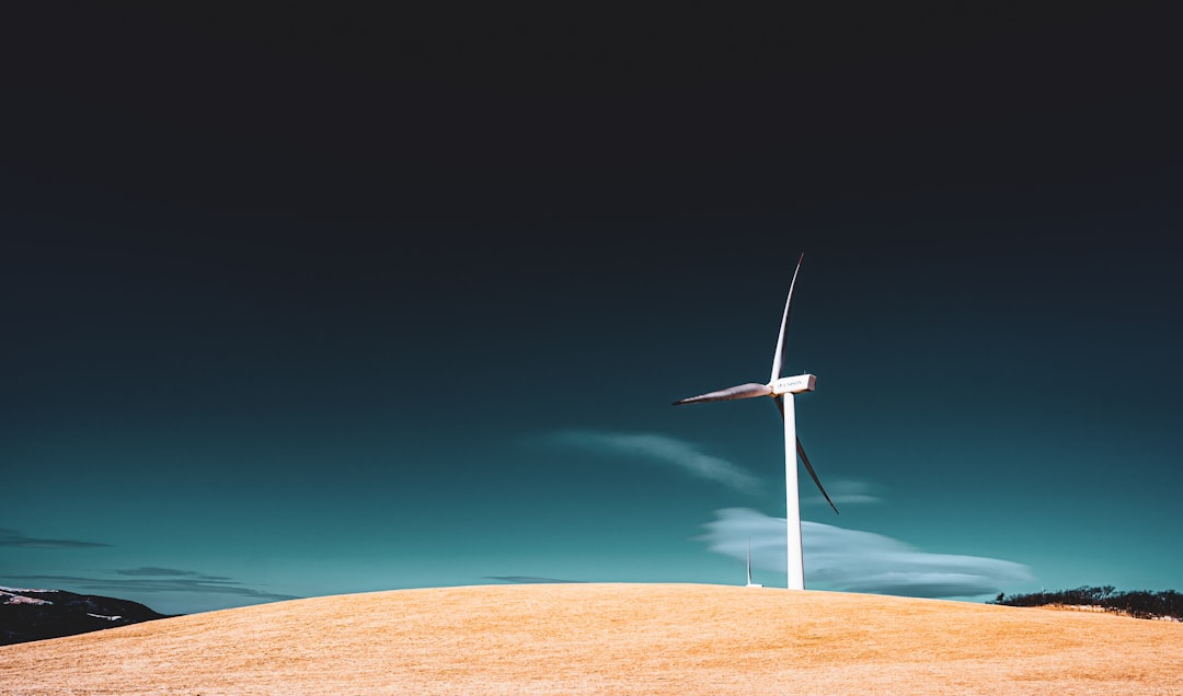 white wind turbine on brown field under blue sky during daytime