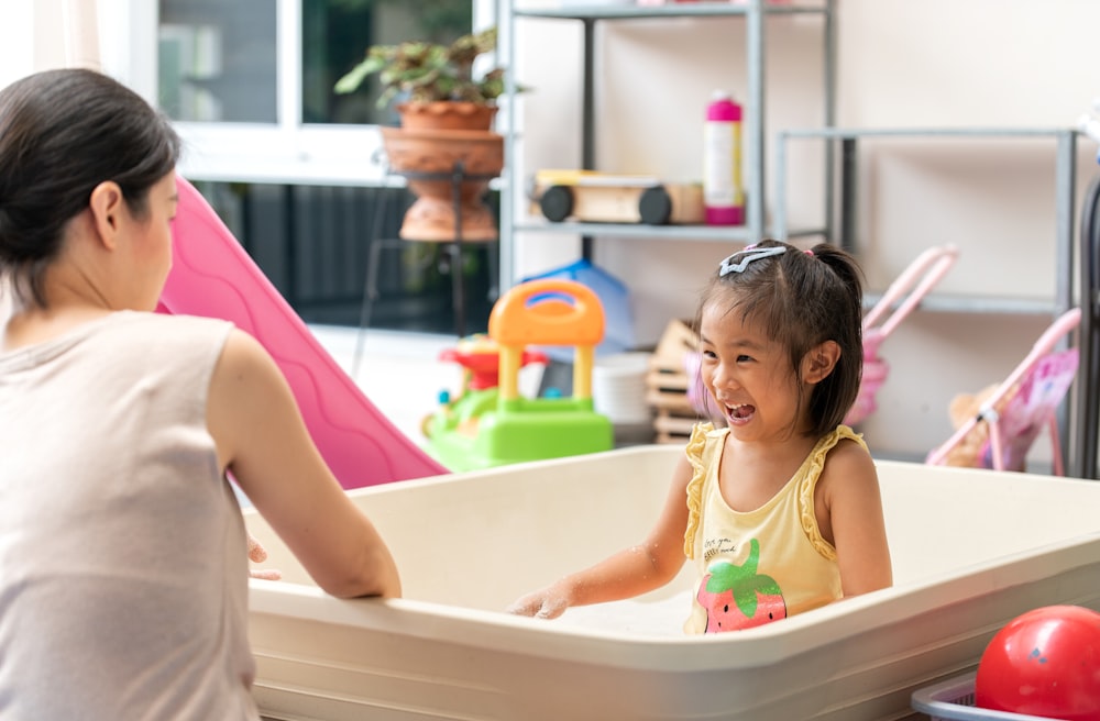 girl in pink tank top sitting on white bathtub