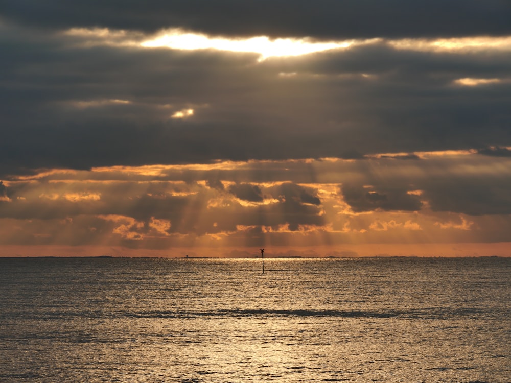 body of water under cloudy sky during sunset