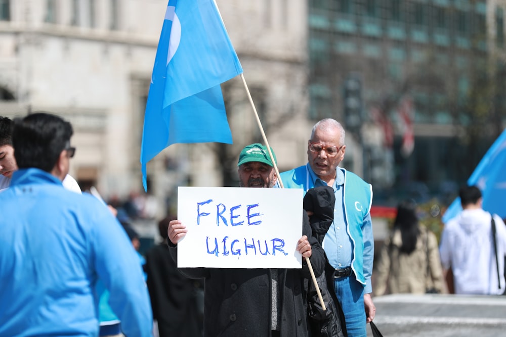 man in blue jacket holding white and blue flag