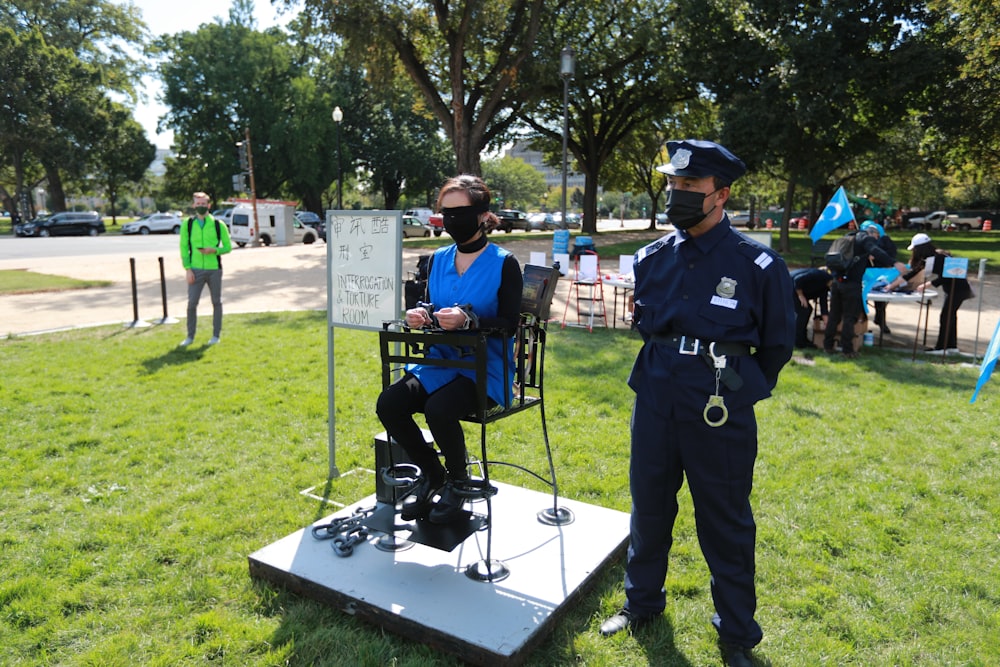 昼間、緑の芝生の上に立つ黒い警官の制服を着た男