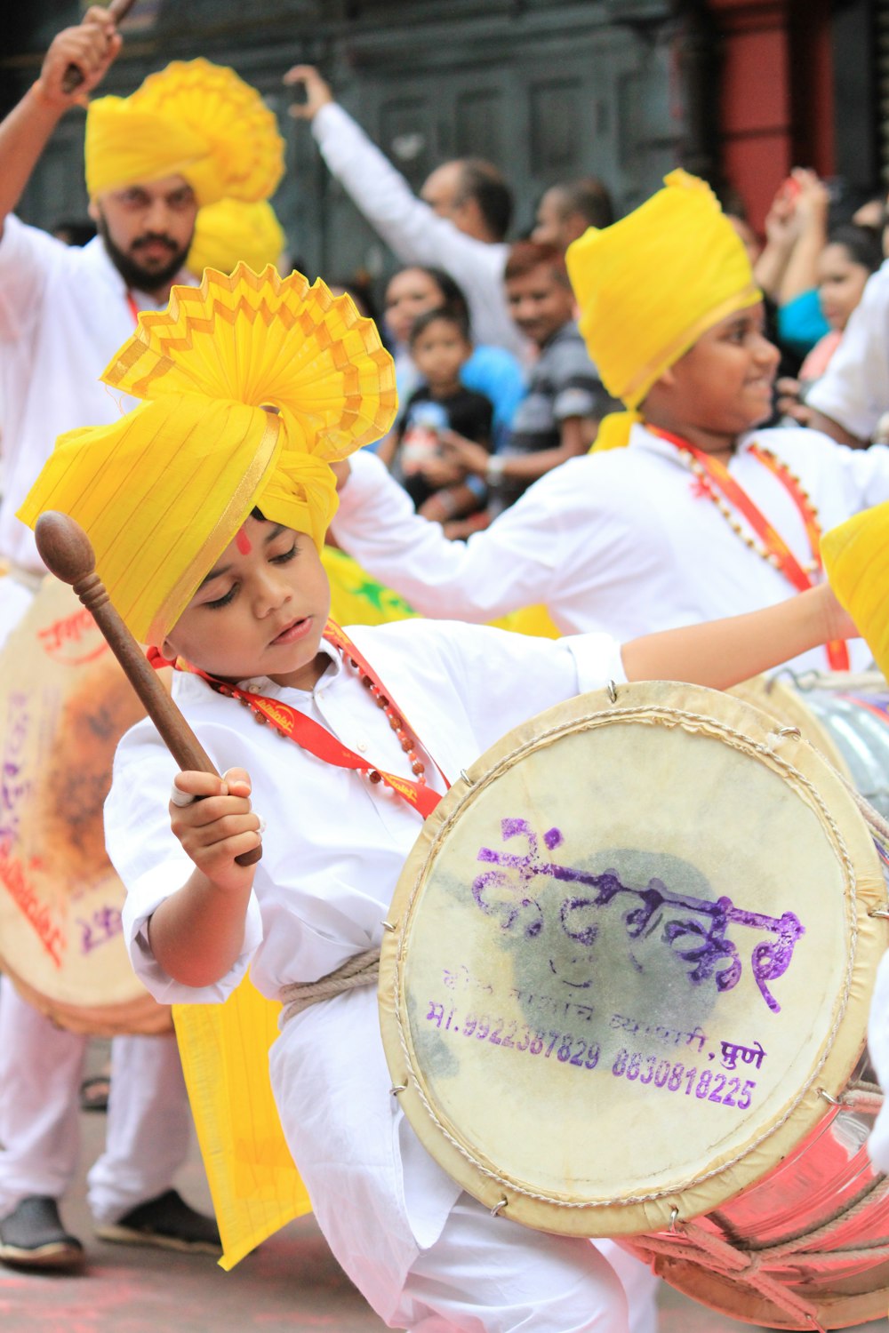 girl in yellow and white dress playing drum