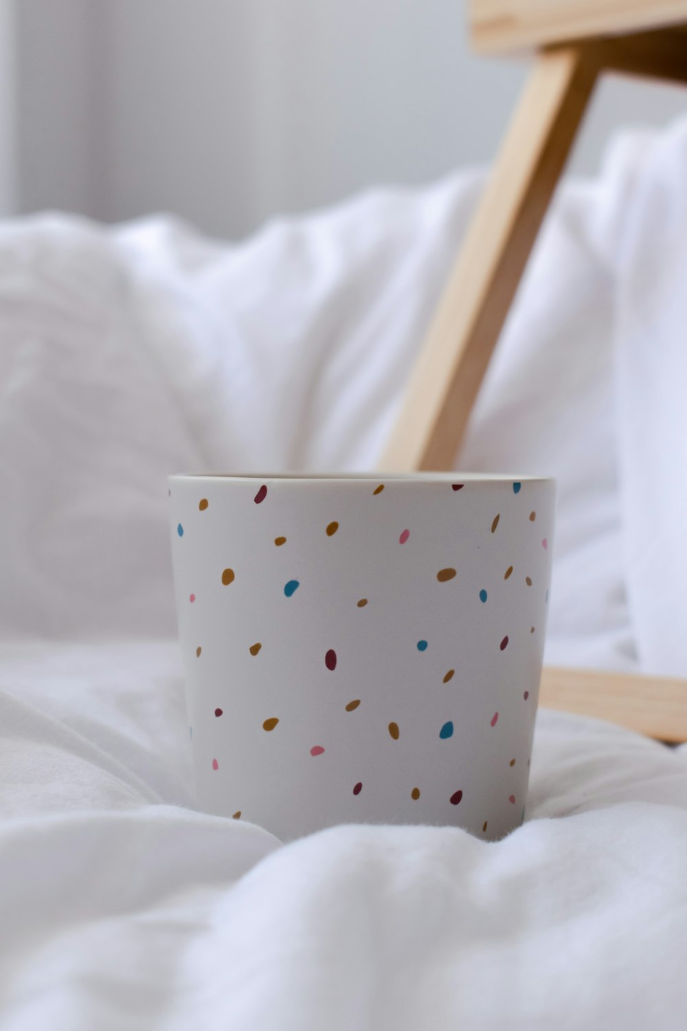 white and black polka dot ceramic mug on white textile