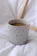 A close-up of a hand-thrown stoneware mug in bright turquoise with a cozy knitted blanket in the background.