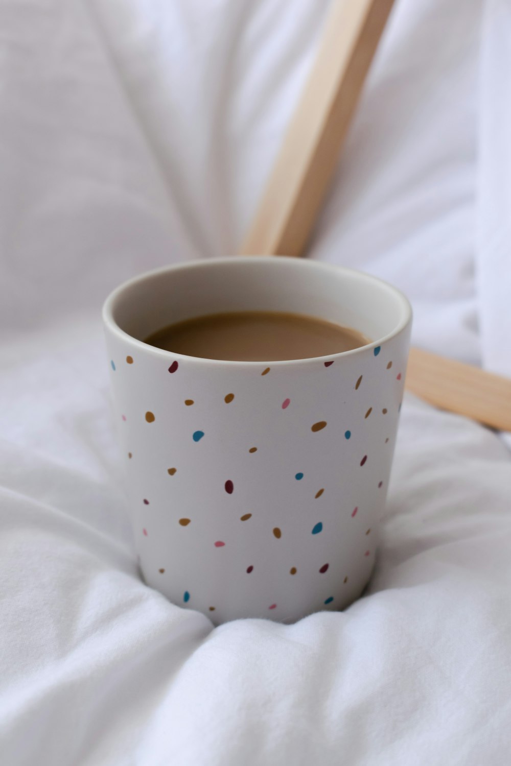 white and blue polka dot ceramic mug on white textile