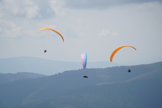 people riding parachute over the mountains during daytime