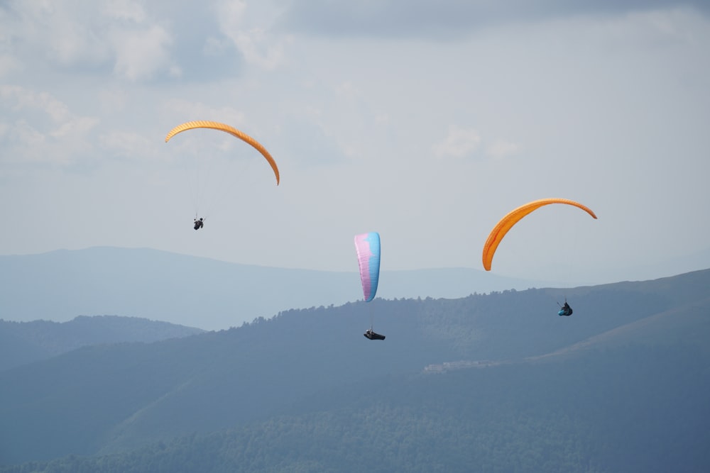 people riding parachute over the mountains during daytime