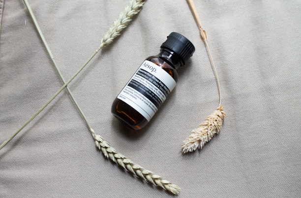 A small amber bottle of Kerassentials oil with fresh green leaves around it.