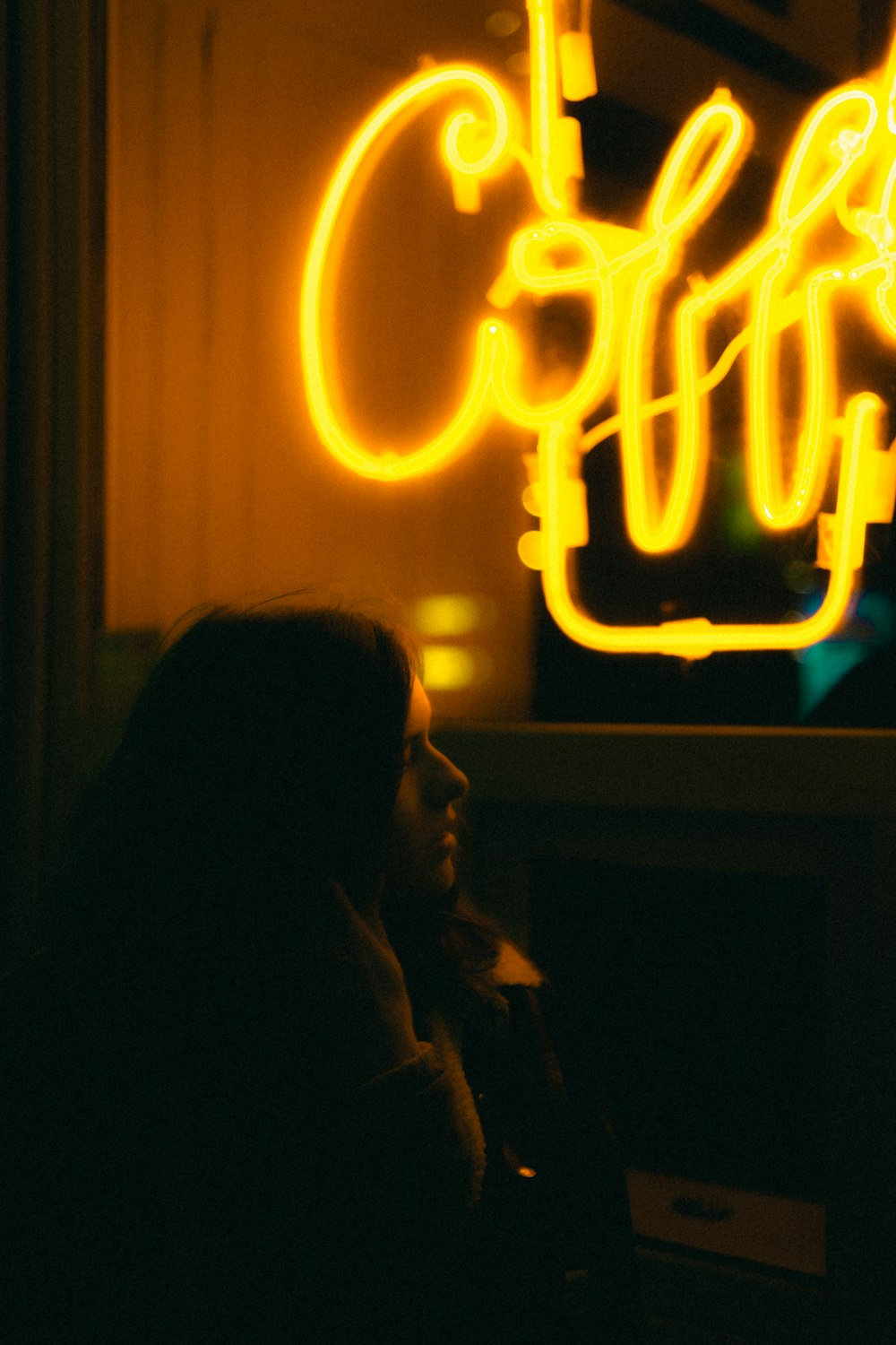 woman in black shirt standing near yellow neon light signage