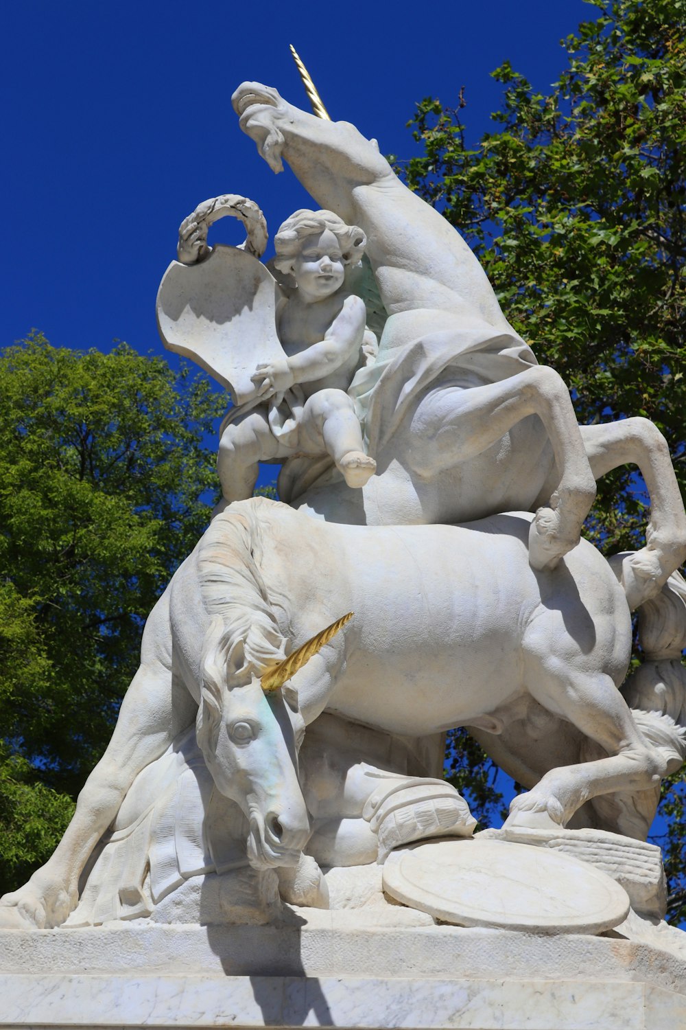 white concrete statue near green trees during daytime