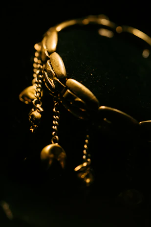 Close-up of a sleek black and gold luxury bracelet resting on a soft nude fabric.