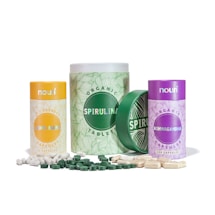 Collection of three cylindrical containers with labels for different dietary supplements. The containers are designed with various colors: yellow for Lion's Mane, green for Spirulina, and purple for Ashwagandha. White and green capsules are scattered around the containers.