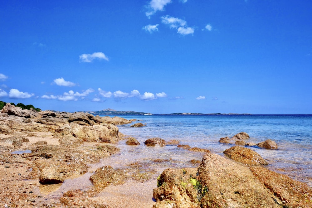 brown rock formation near blue sea under blue sky during daytime