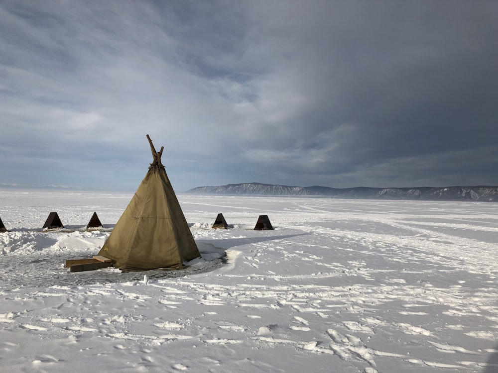 brown tent on snow covered ground under white clouds during daytime